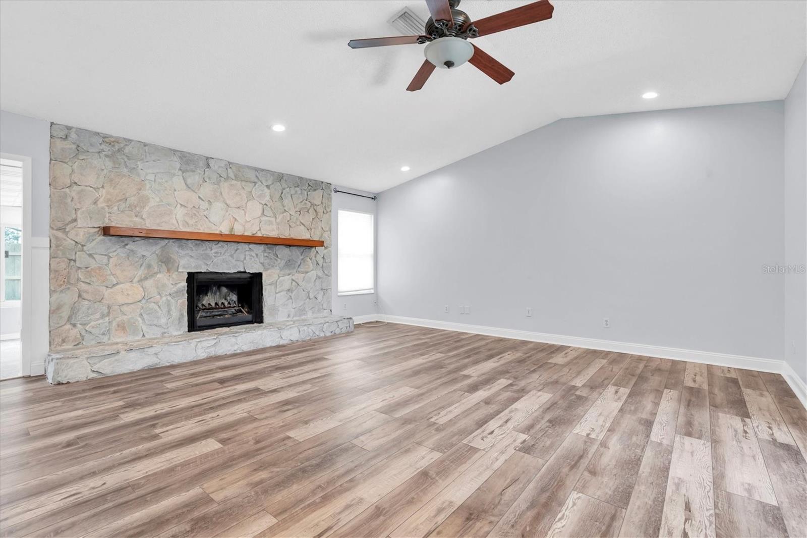 Unfurnished views of living area and wood burning fireplace provided to showcase space and support your own decorating ideas.