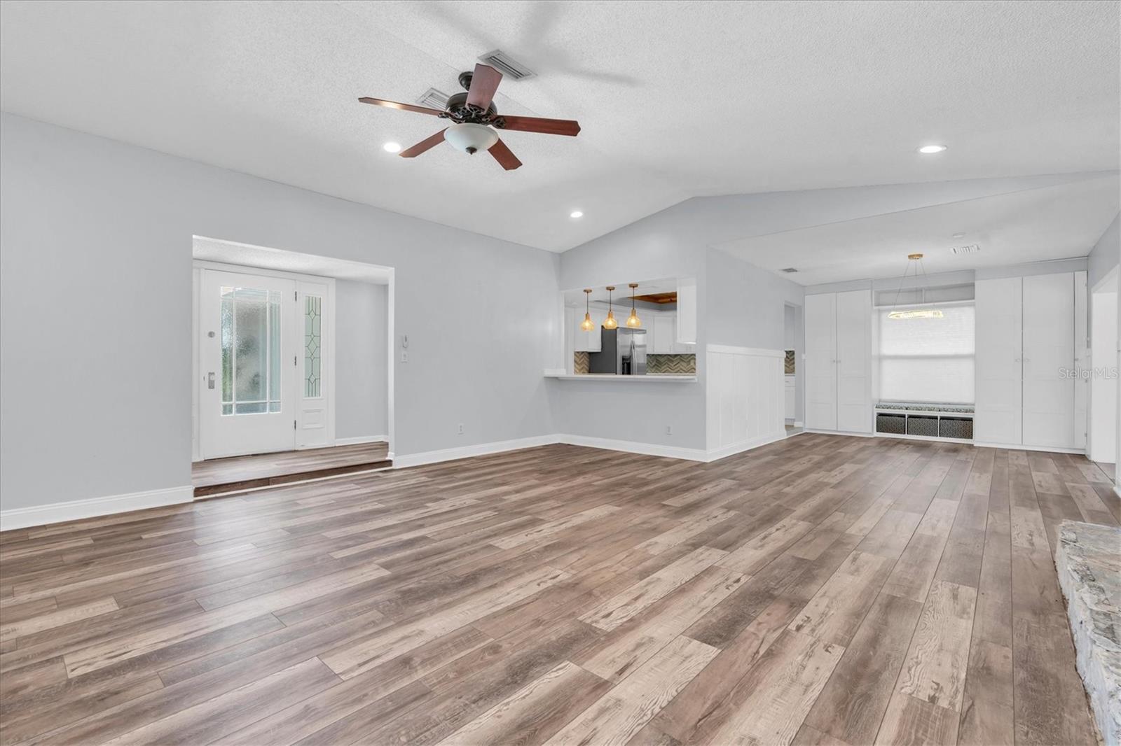 Unfurnished views of living, dining, open bar to kitchen, and foyer provided to showcase space and support your own decorating ideas.