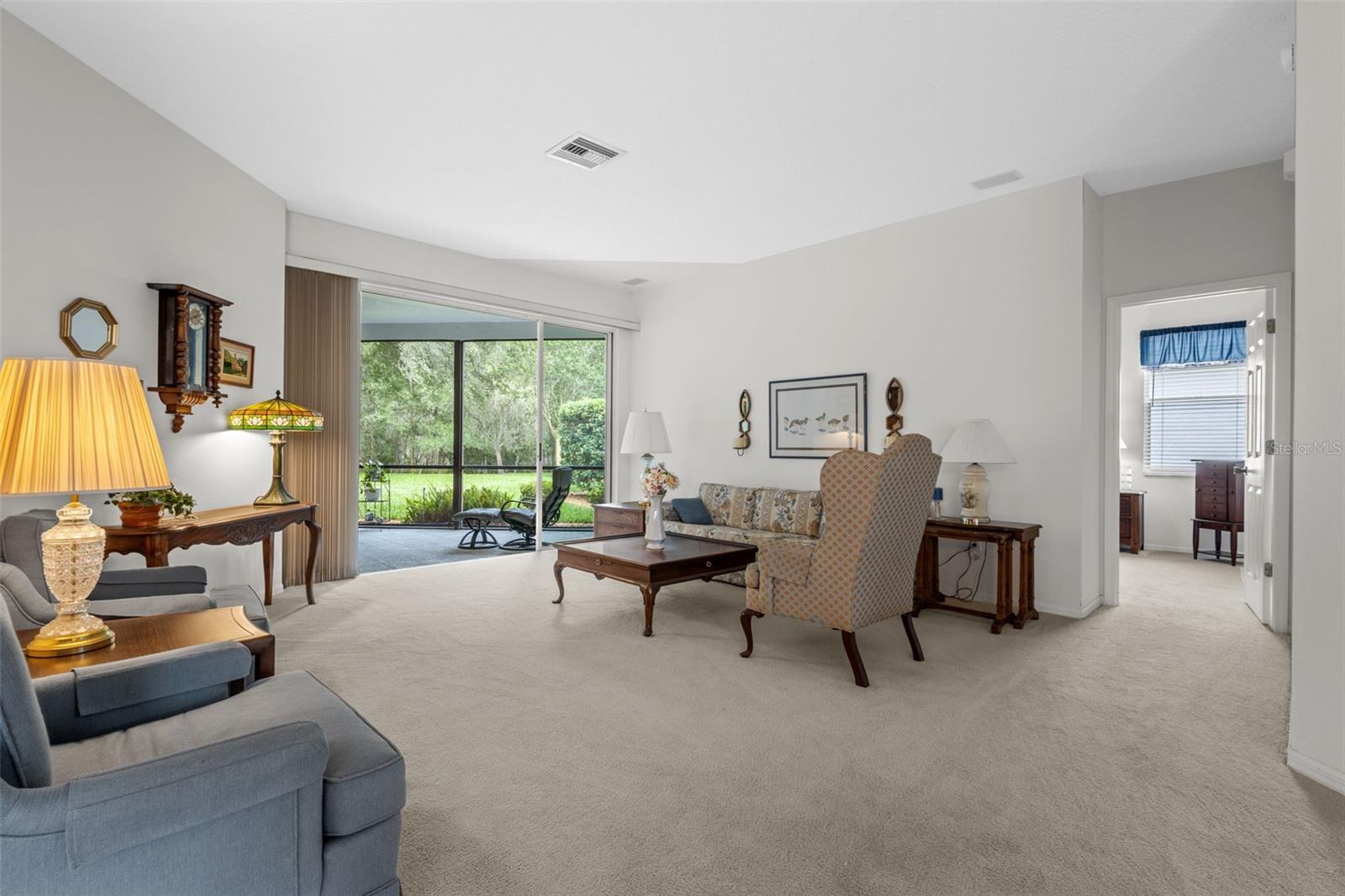 Formal living room has sliders to the outdoor screened in porch and beautiful views. Doorway on right is to primary suite
