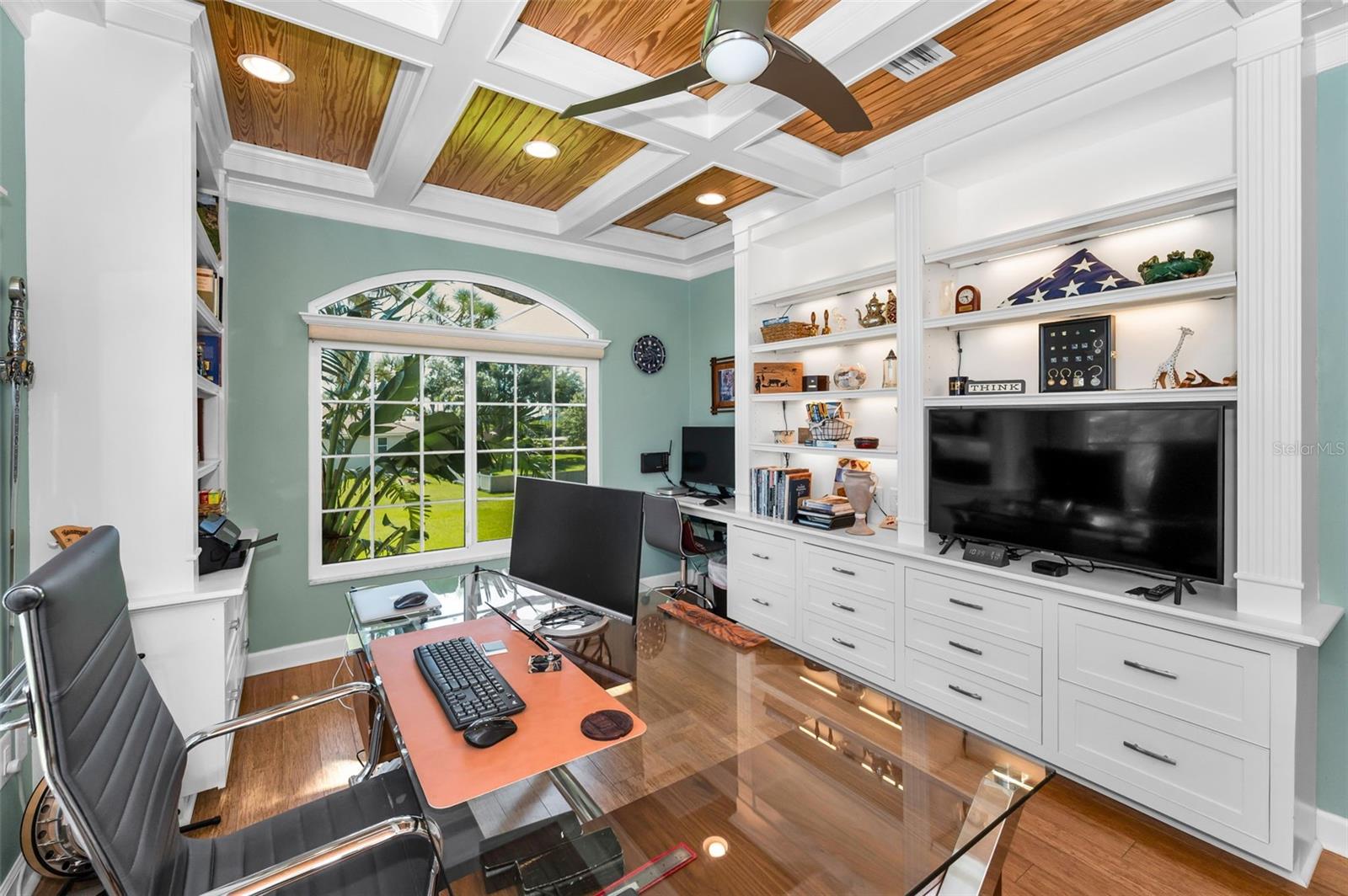 Office with custom bult-in cabinetry and coffered ceiling with wood paneled insets