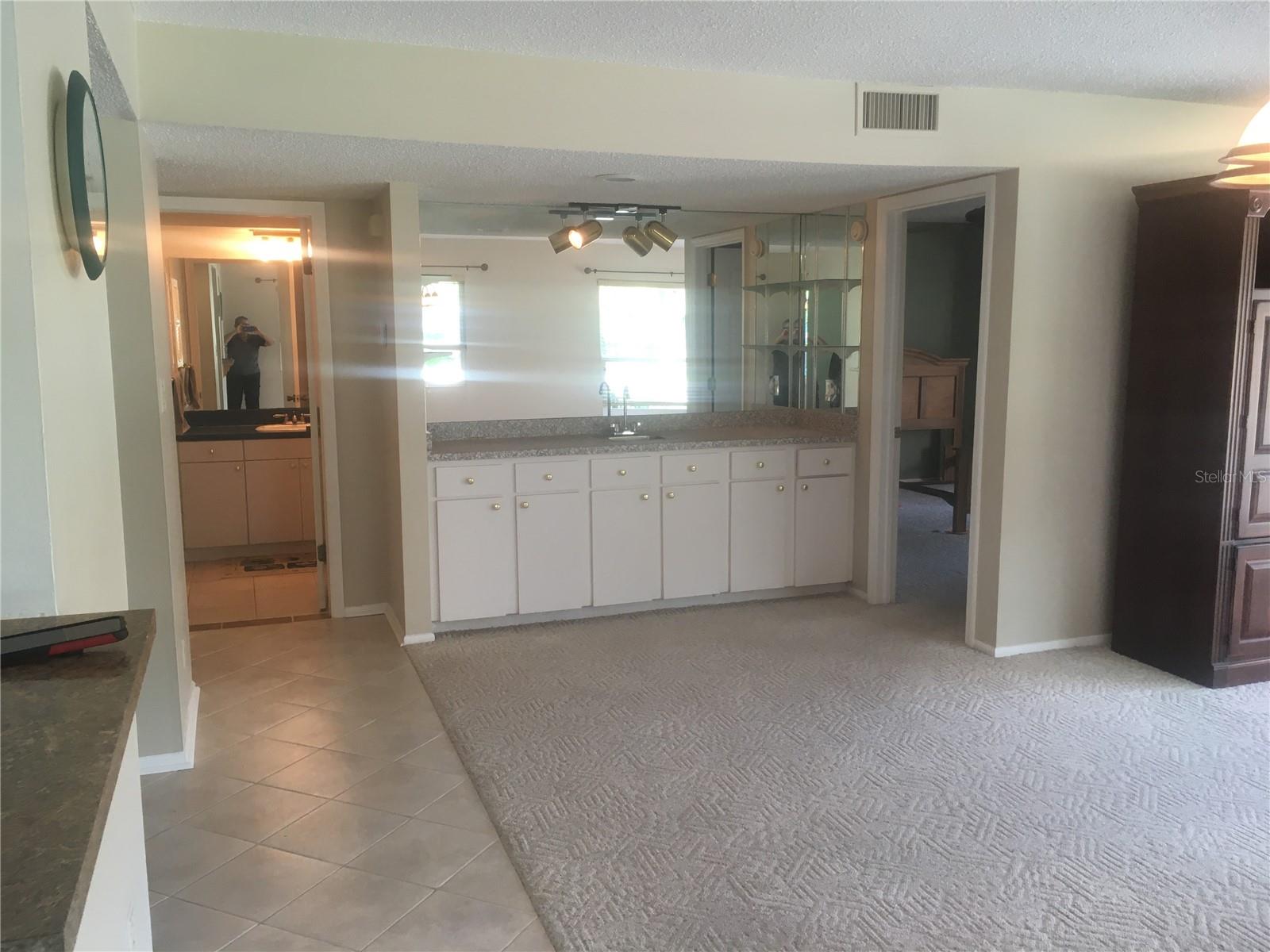 From kitchen doorway - kitchen passthrough on left, guest bathroom at end of tile, wet bar and doorway into master bedroom