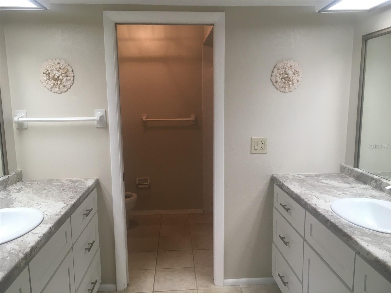 Dual vanities and sinks. Toilet and shower through pocket doorway