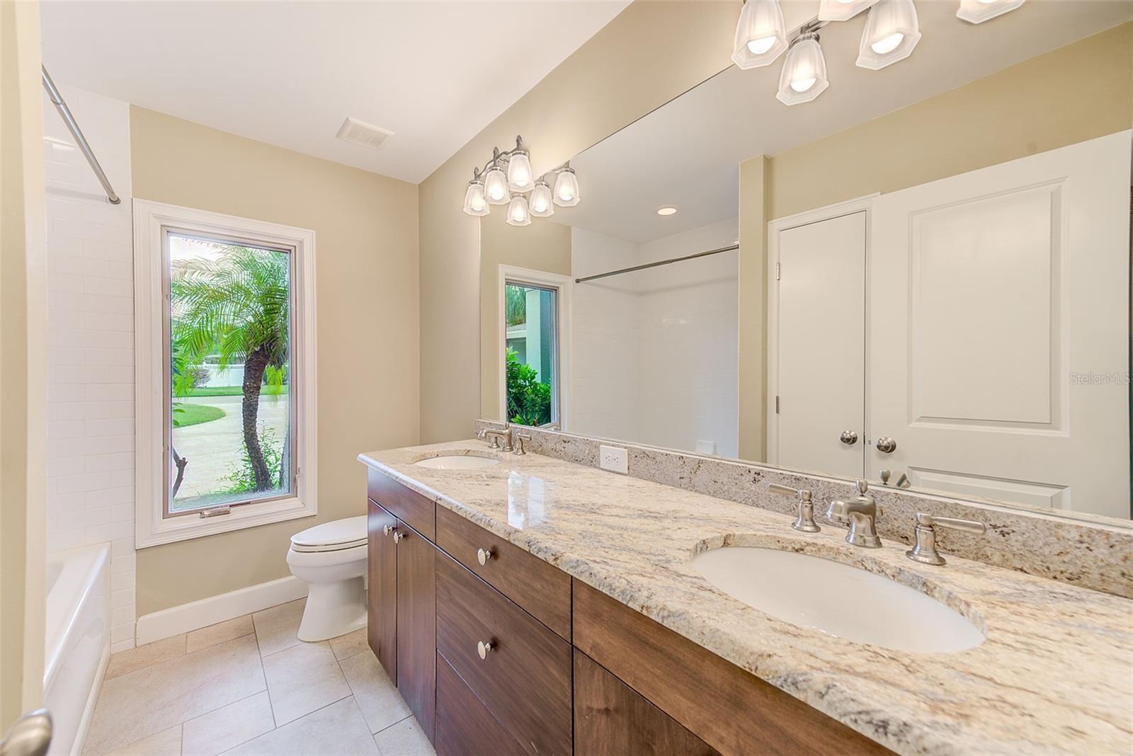 Bathroom 2 with custom cabinetry, granite, and dual vanity