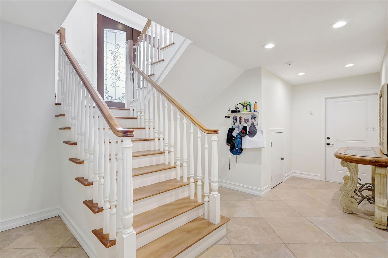 The custom built home features a staircase leading to the ground floor.  The foyer is spacious leading to the garages, and back yard.