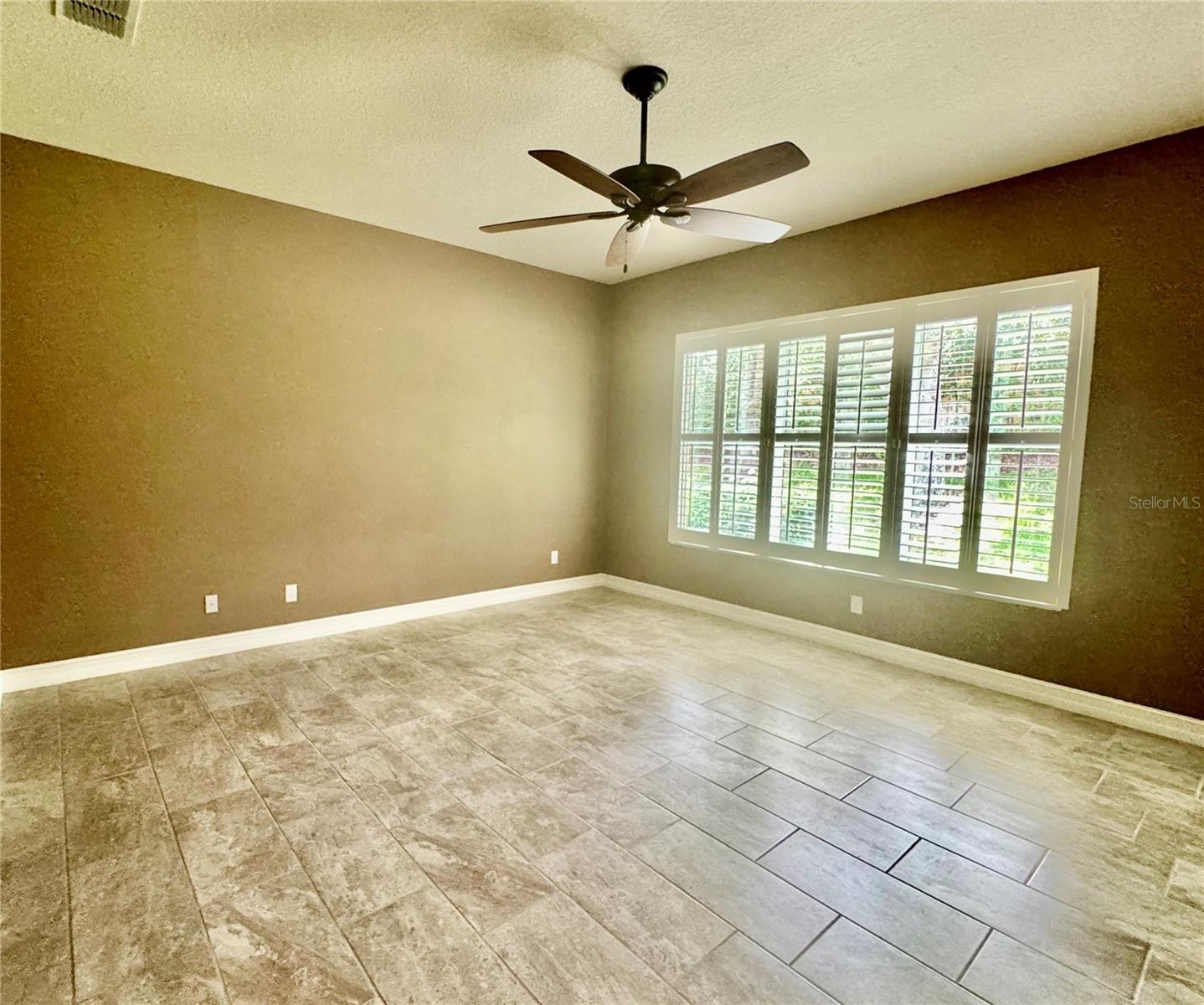 OWNER'S SUITE FEATURES WALL OF WINDOWS W/PLANTATION SHUTTERS & PORCELAIN TILE FLOOR