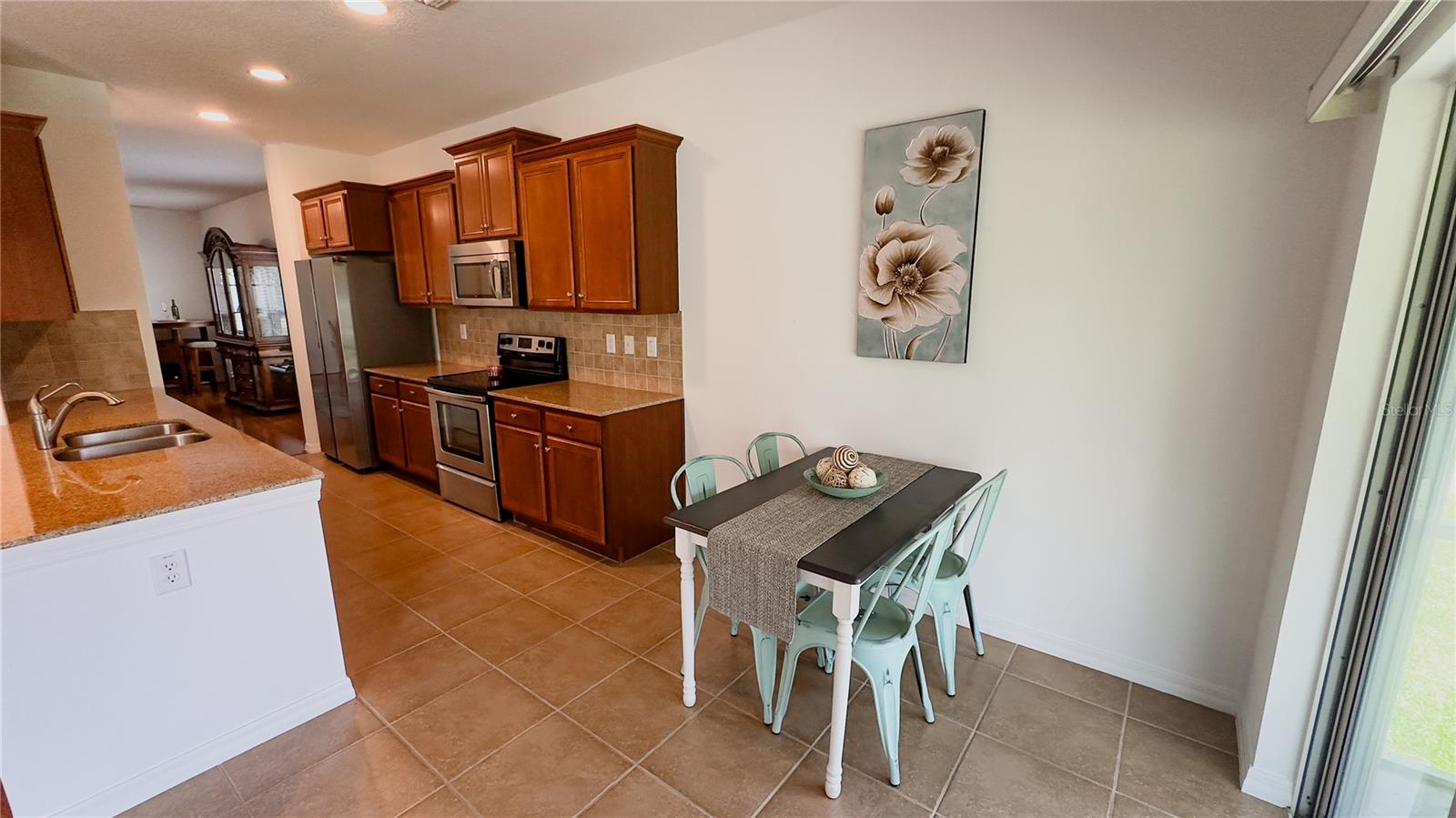 Eat-In Kitchen area next to cherry wood kitchen cabinets and stainless appliances.