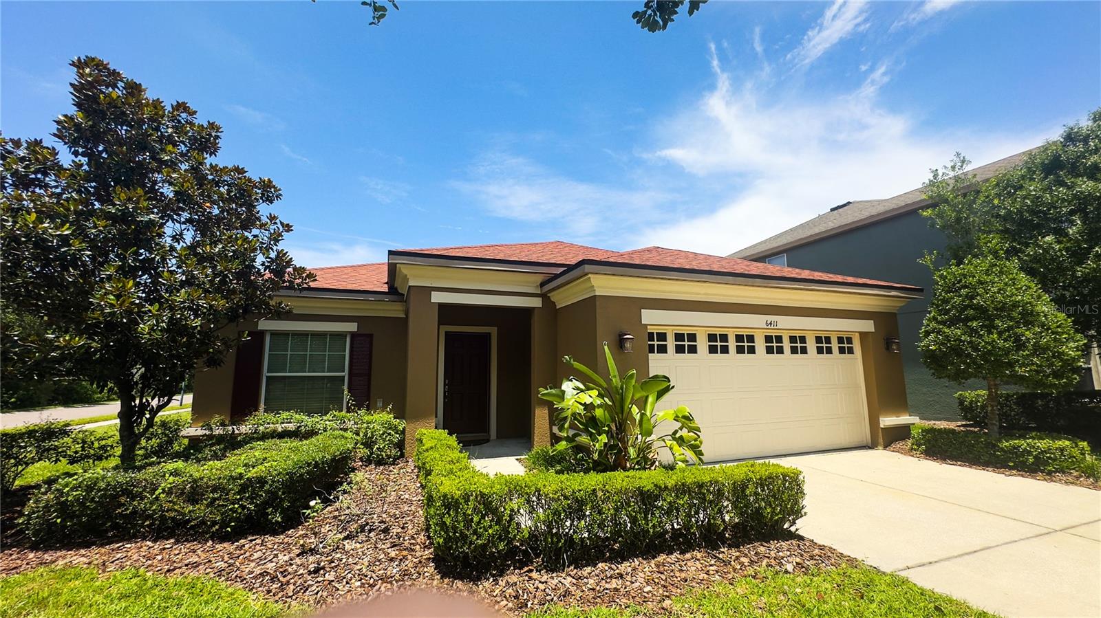 Covered front entrance surrounded by landscaping for added privacy.