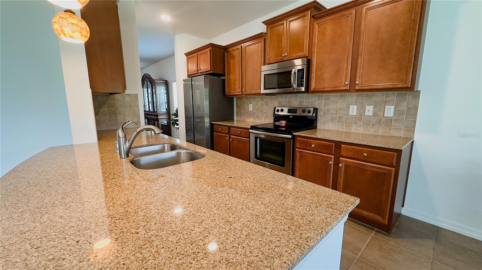 Spacious granite counters for serving and prepping, cherry wood cabinets, tile backsplash and stainless appliances