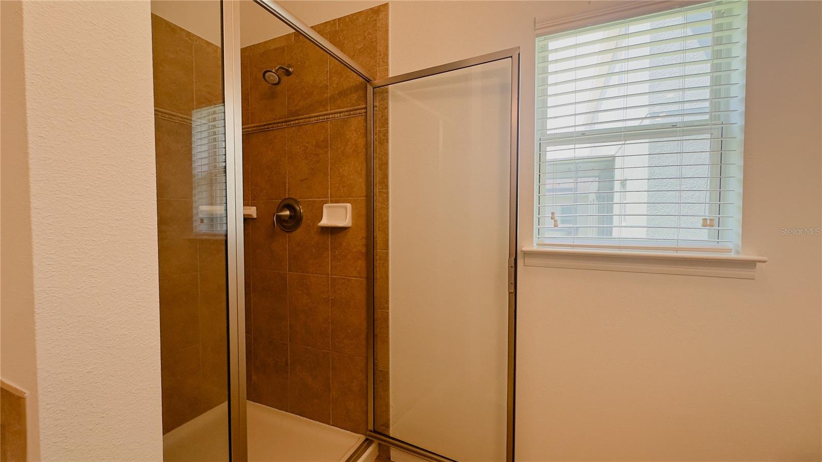 Glass enclosed tiled master bath walk-in shower