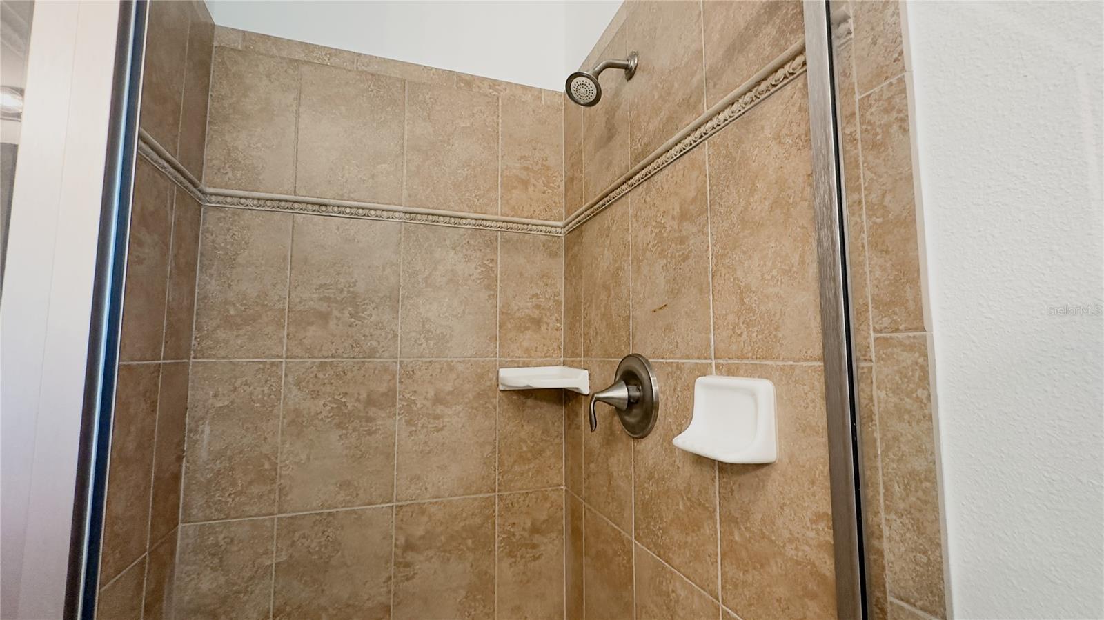 Tiled walk-in shower with decorative molding detail.