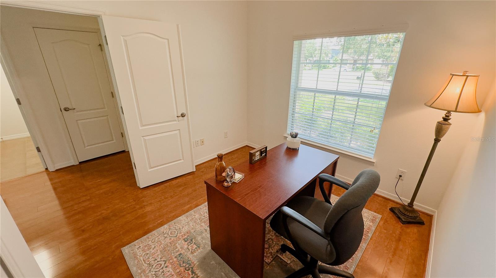 Bedroom 1 staged as office overlooks the front yard and is split from the other bedrooms for added privacy.