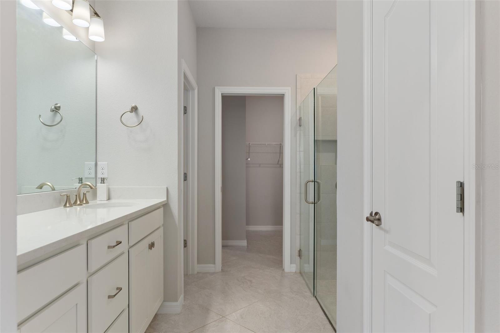 Primary bath with dual vanities and quart counters. Frameless shower and huge walk in closets