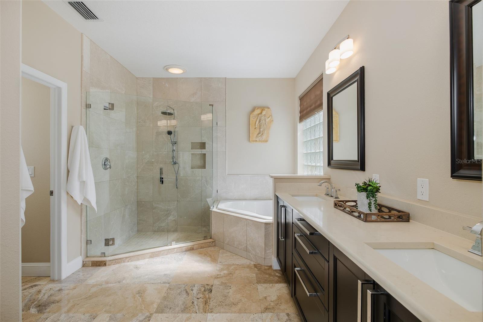 Luxurious Primary bath with garden tub, travertine lined shower, dual sinks and water closet