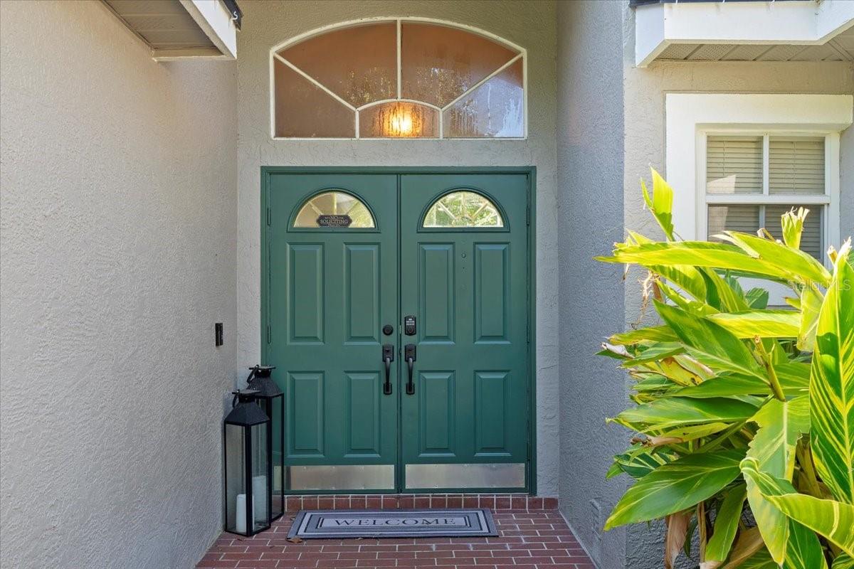 Covered front entry way with double doors and large decorative transom window.