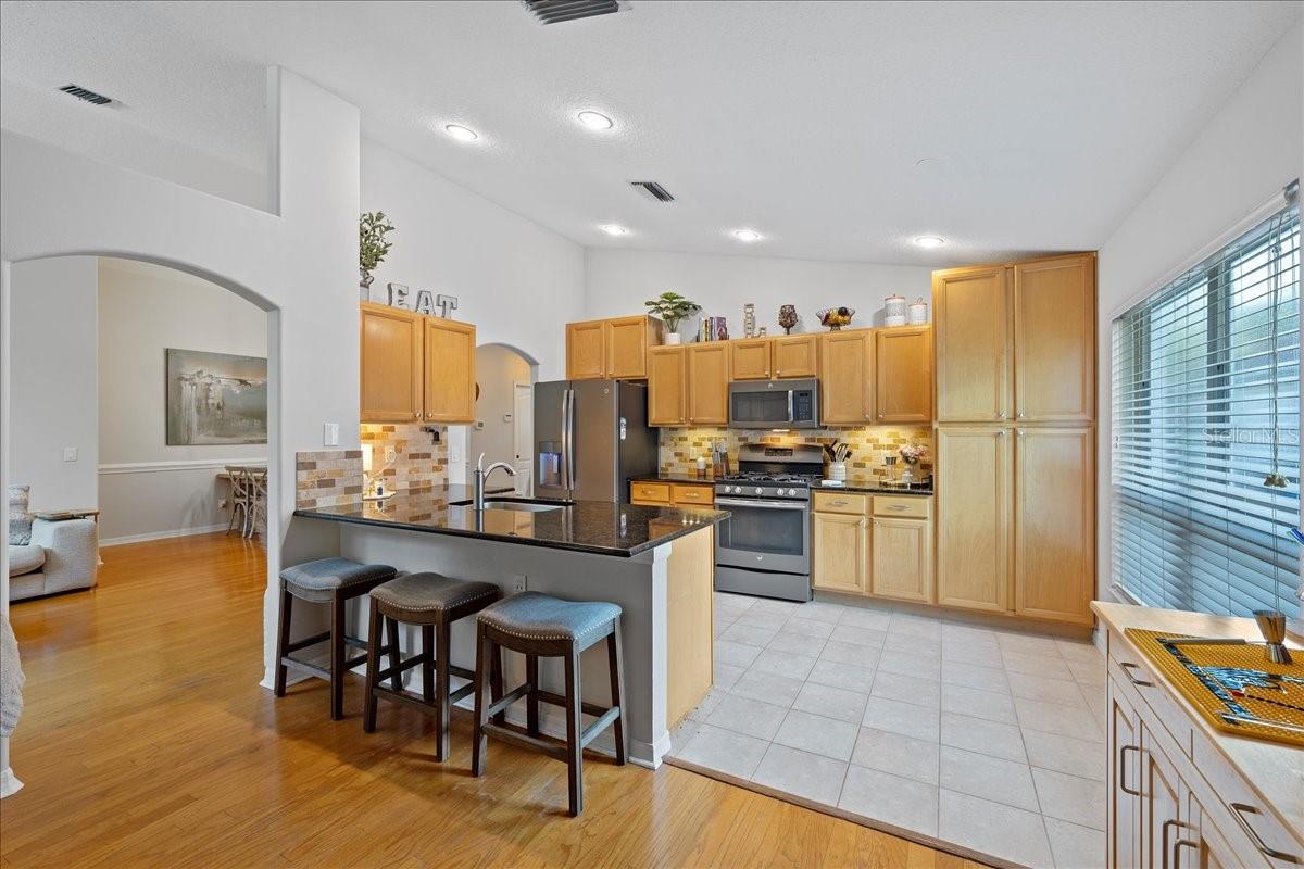 Open concept kitchen is well -equipped with stainless steel appliances, ceramic tile floors, and breakfast bar