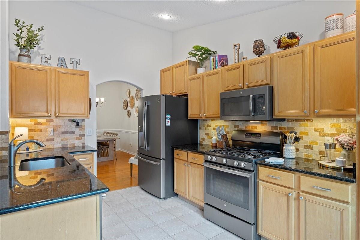 Open concept kitchen is well -equipped with stainless steel appliances, ceramic tile floors, and breakfast bar
