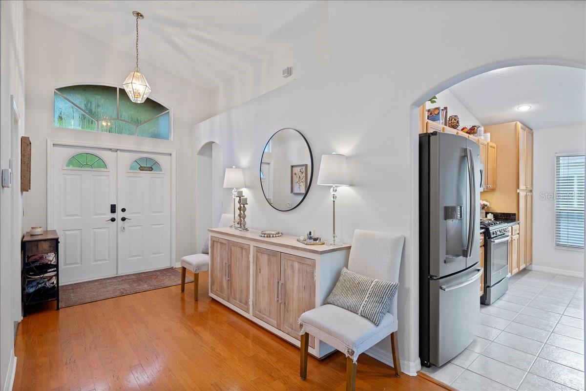 Open and airy foyer with high ceilings, natural lighting and a decorative pendant light.
