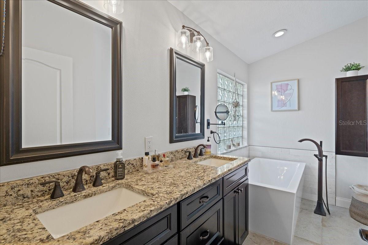 Primary ensuite bathroom with dual sink vanity, modern fixtures, soaking tub and large stand-up shower