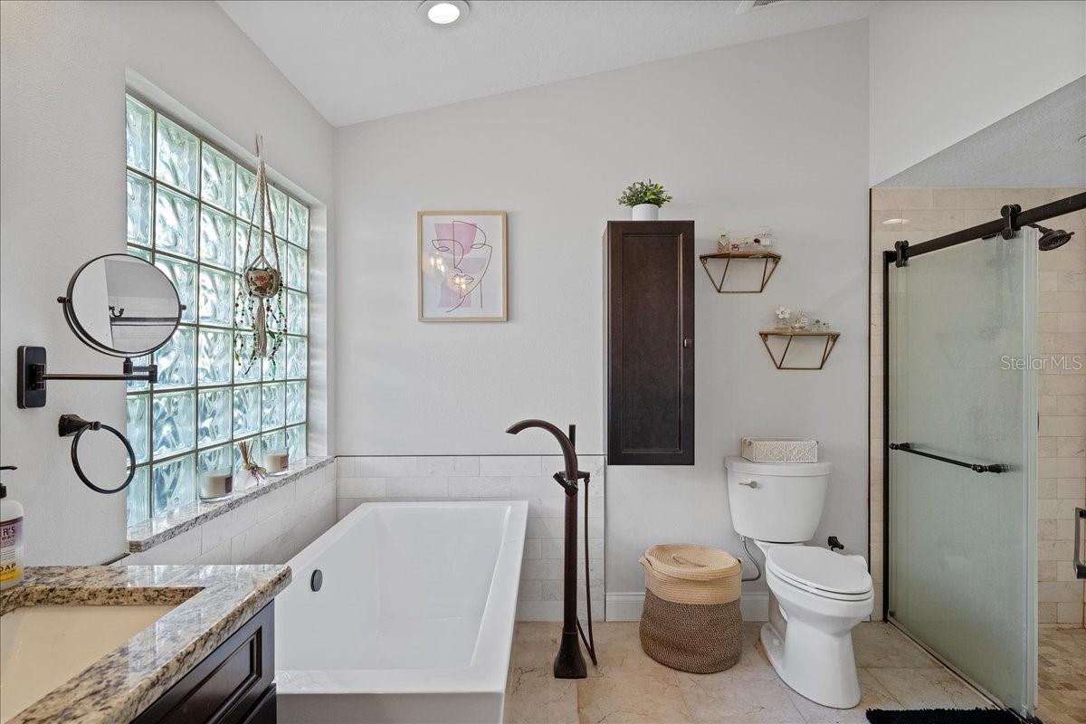 Primary ensuite bathroom with dual sink vanity, modern fixtures, soaking tub and large stand-up shower