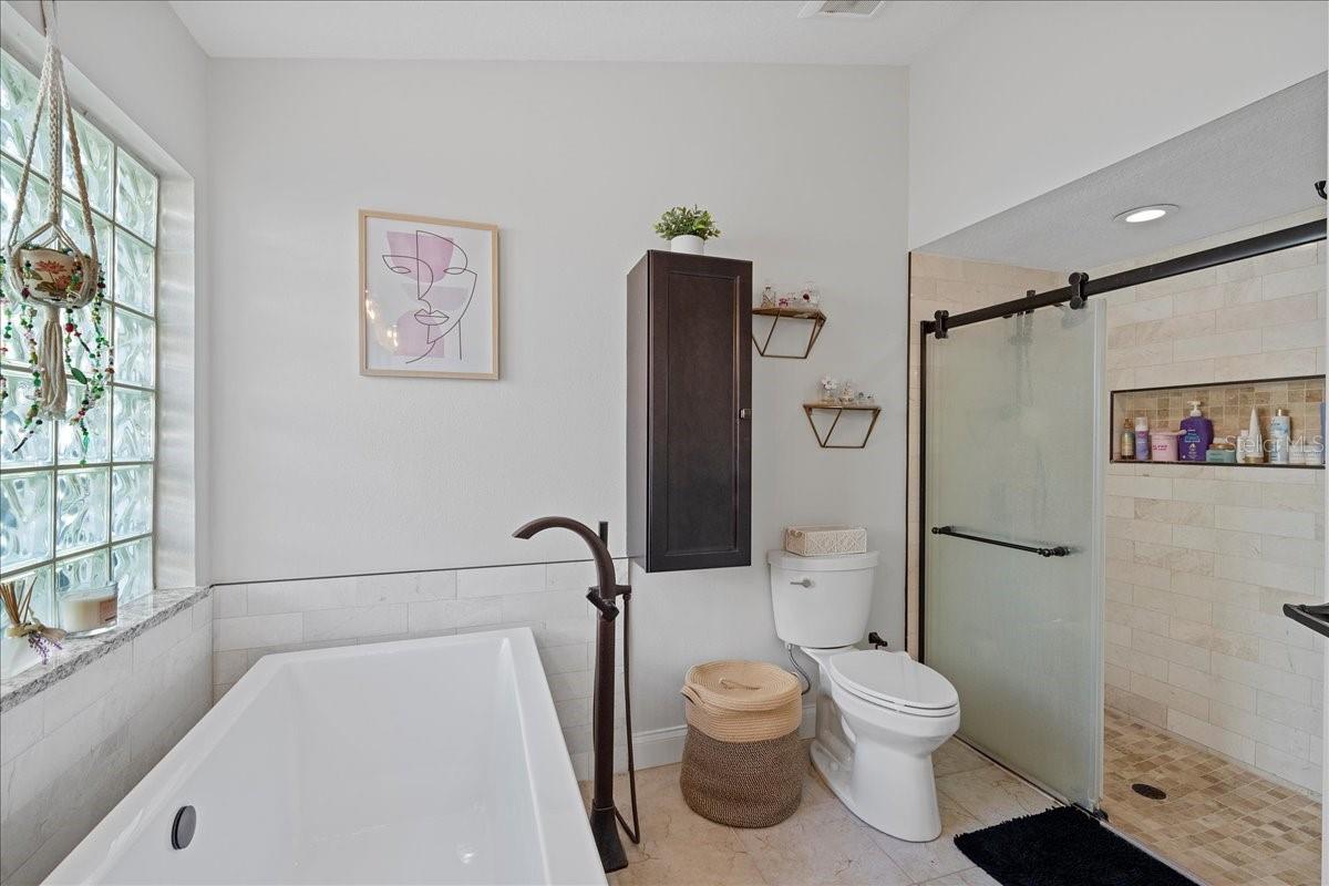 Primary ensuite bathroom with dual sink vanity, modern fixtures, soaking tub and large stand-up shower