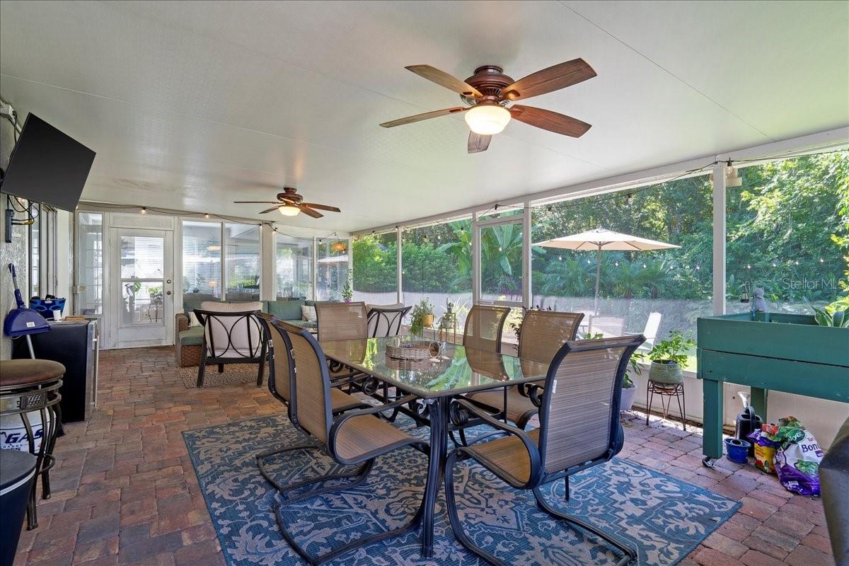 Spacious screened-in patio with paver tile flooring, two ceiling fans and glass sliders from the living room and door to the Florida room/sunroom offers a protected outdoor setting ideal for year-round enjoyment.