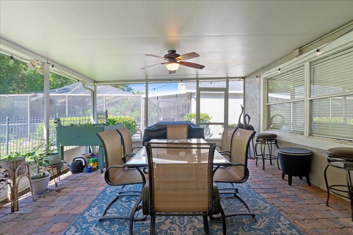 Spacious screened-in patio with paver tile flooring, two ceiling fans and glass sliders from the living room and door to the Florida room/sunroom offers a protected outdoor setting ideal for year-round enjoyment.