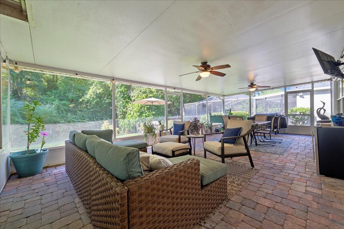 Spacious screened-in patio with paver tile flooring, two ceiling fans and glass sliders from the living room and door to the Florida room/sunroom offers a protected outdoor setting ideal for year-round enjoyment.