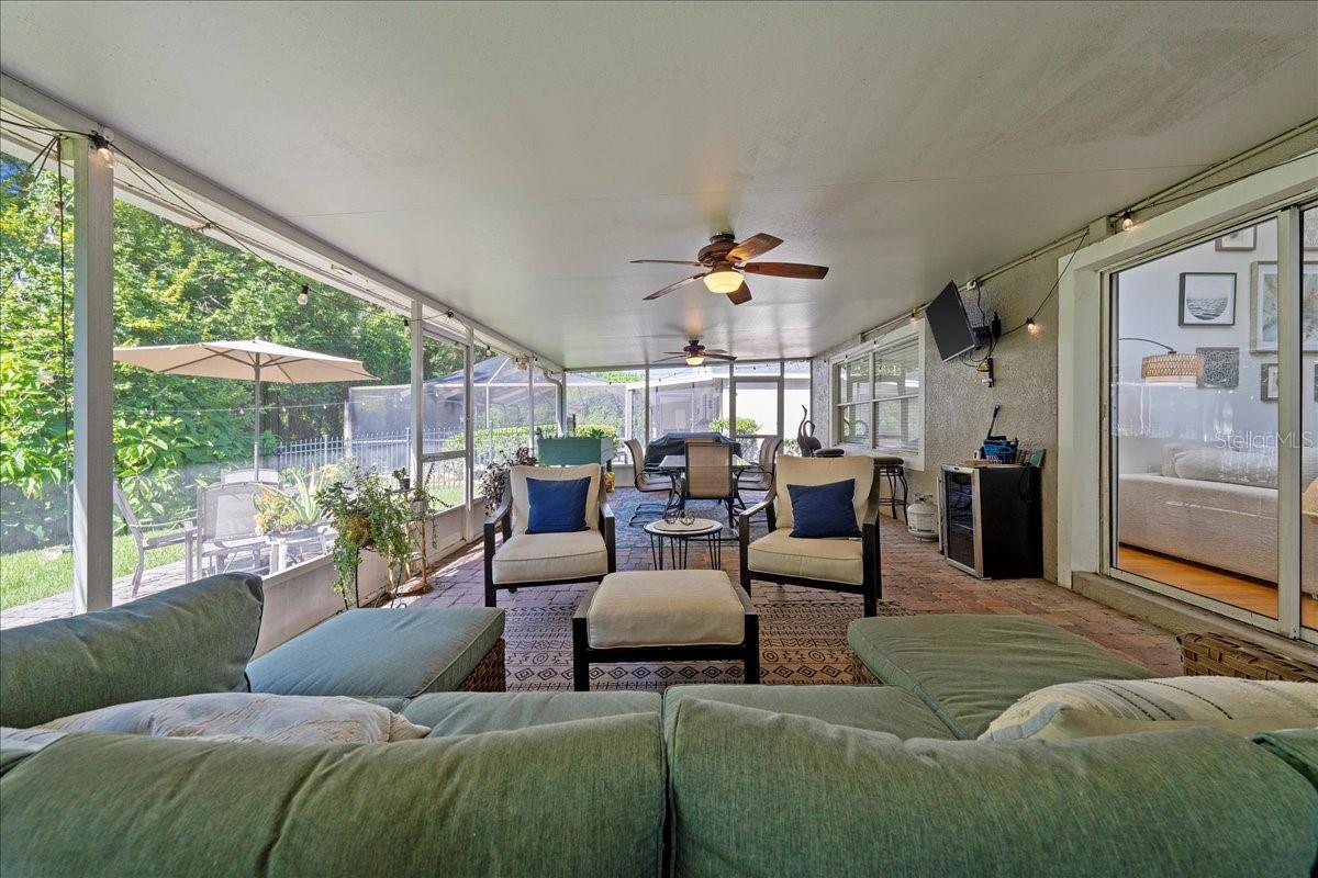 Spacious screened-in patio with paver tile flooring, two ceiling fans and glass sliders from the living room and door to the Florida room/sunroom offers a protected outdoor setting ideal for year-round enjoyment.