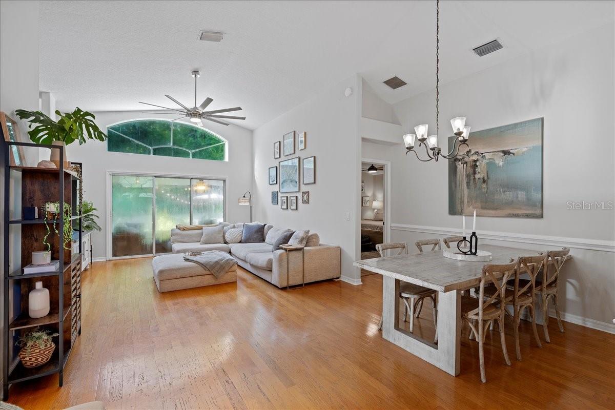 Living room and dining room with vaulted ceilings, oak wood floors and triple glass sliders out to the screened-in patio