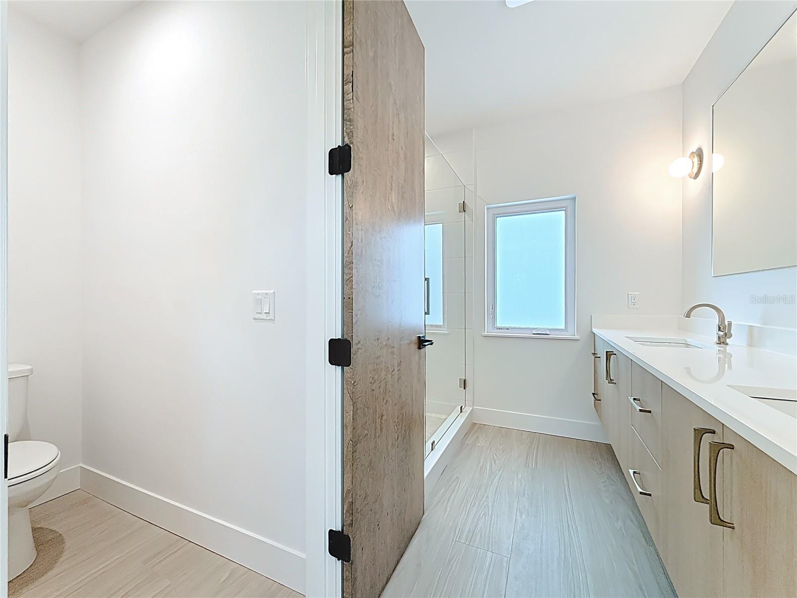 Spa-like en-suite bath featuring dual sinks, an oversized walk-in shower, and a private water closet.