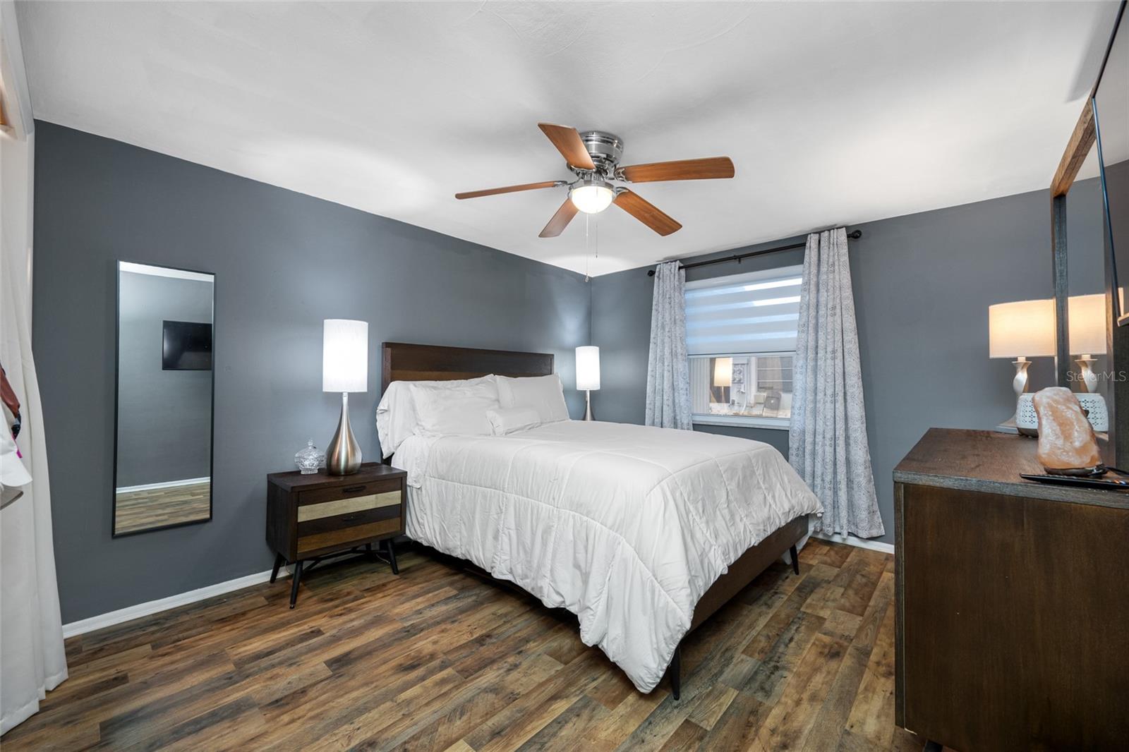 Primary bedroom has lighted fan, LVP flooring, updated window with custom blind and updated built in closet
