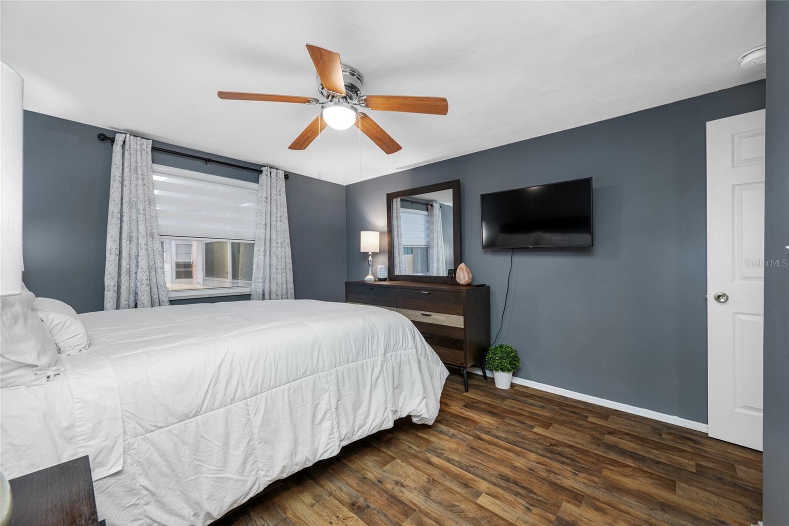 Primary bedroom has lighted fan, LVP flooring, updated window and custom blind, updated built in closet