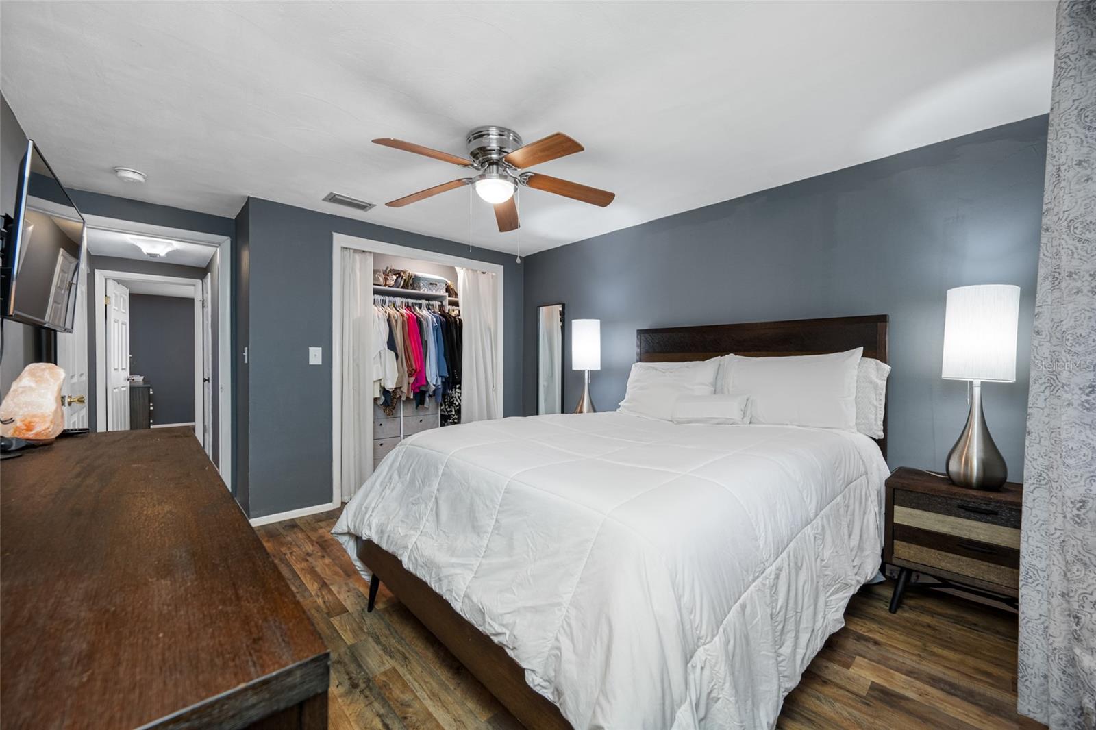 Primary bedroom has lighted fan, LVP flooring, updated window and updated built in closet