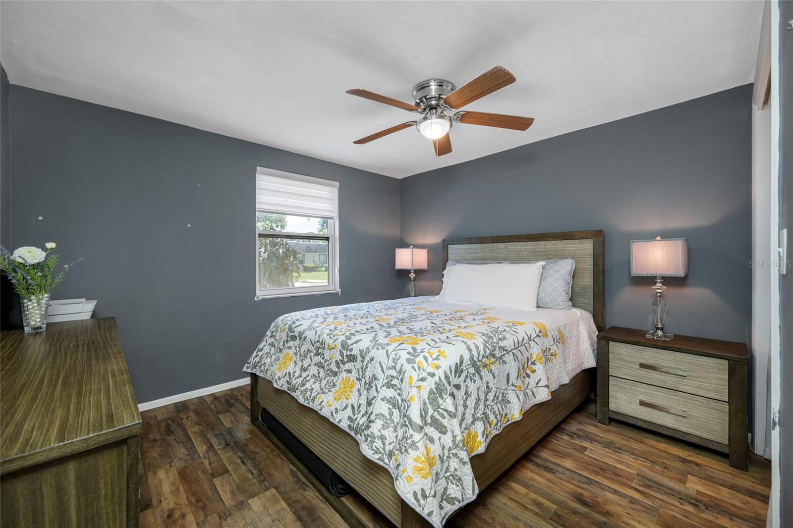 Second bedroom has updated lighted fan, built in closet, LVP flooring and custom shade.