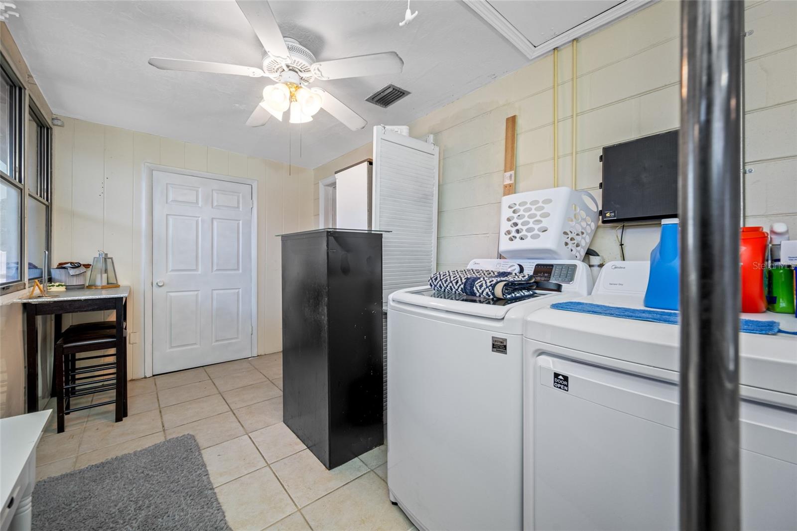 Flex space leading to back yard doubles as private inside laundry with large wash sink and storage closet.