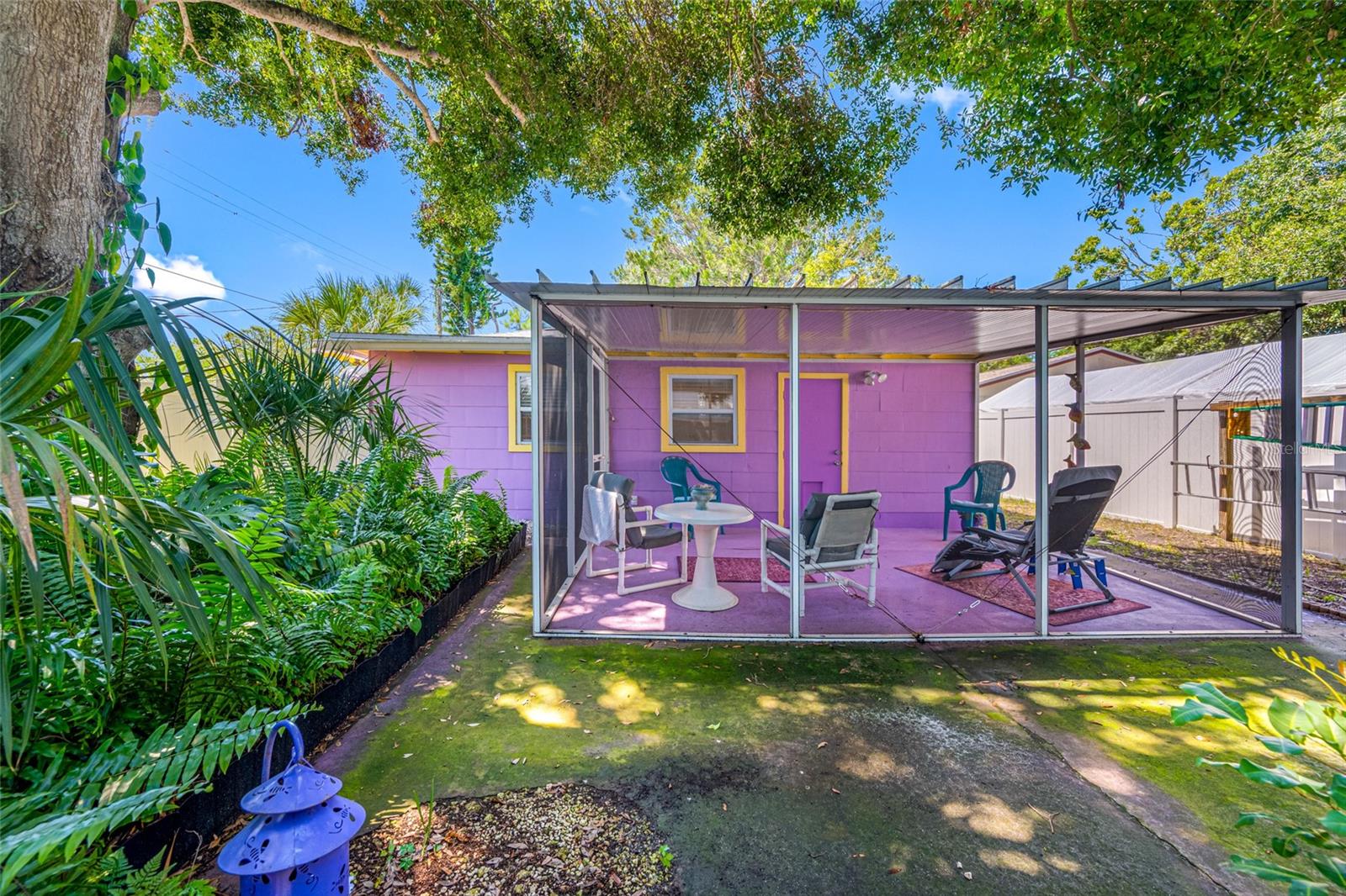 Tucked beneath a canopy of mature trees, this serene rear screened porch offers the perfect blend of comfort and nature
