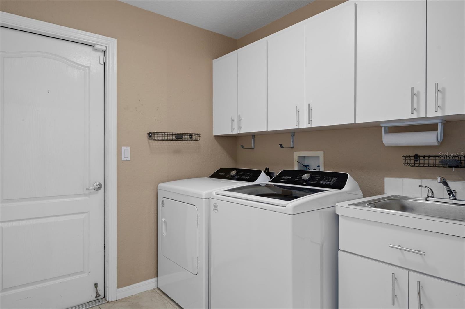 The inside laundry room has a washer and dryer that do stay and is equipped with a sink and cabinets for ample storage.
