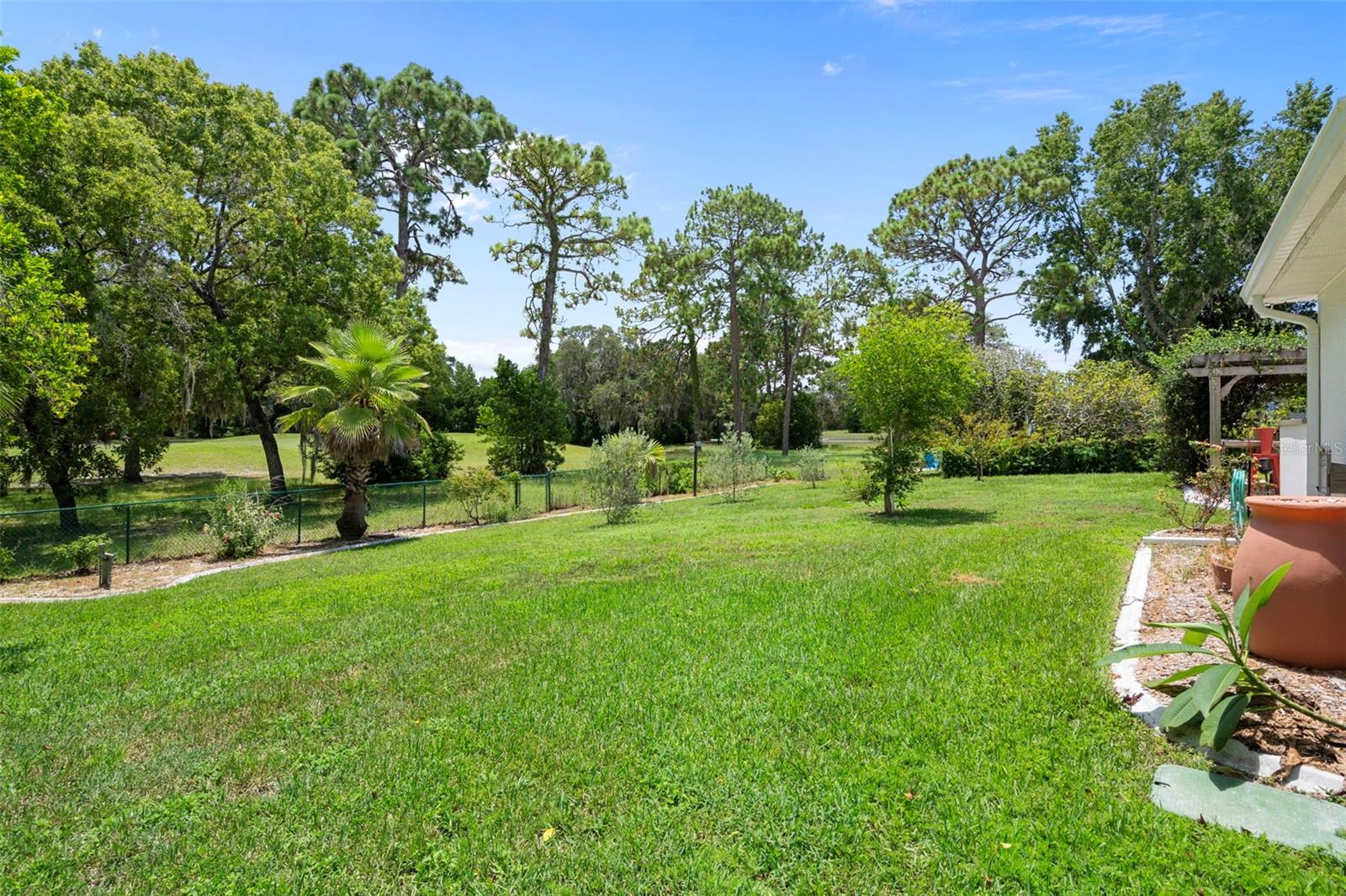 View of the fenced in park-like backyard and the golf course