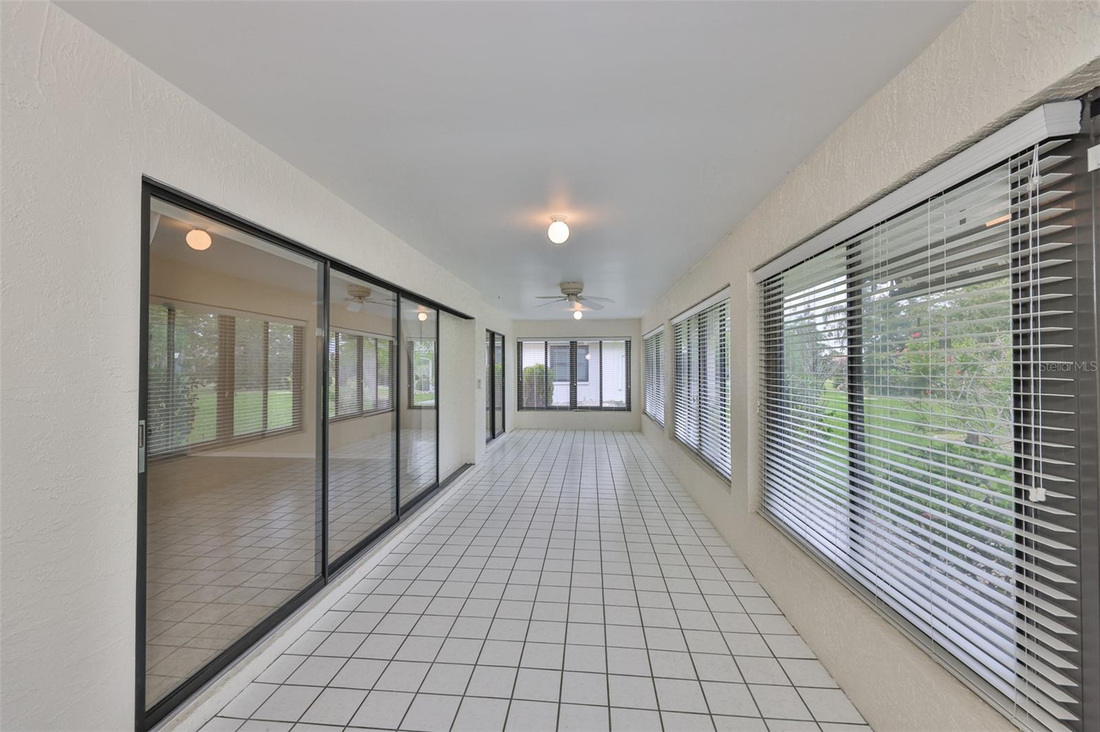 Expansive Florida Room, four season, heated and air conditioned. Disappearing wall near left, sliders to primary bedroom far left. Garden view. Door on immediate right to patio with awning and garden.