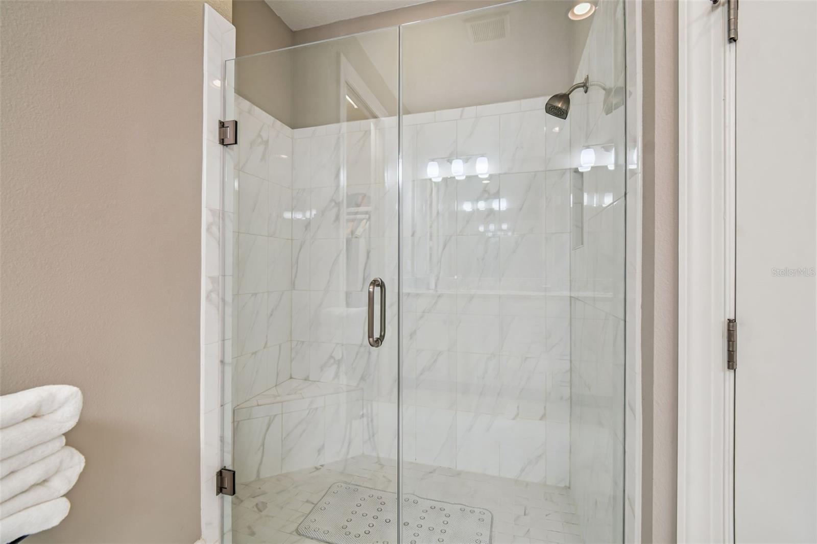 Upgraded walk in shower with glass doors and detailed tile