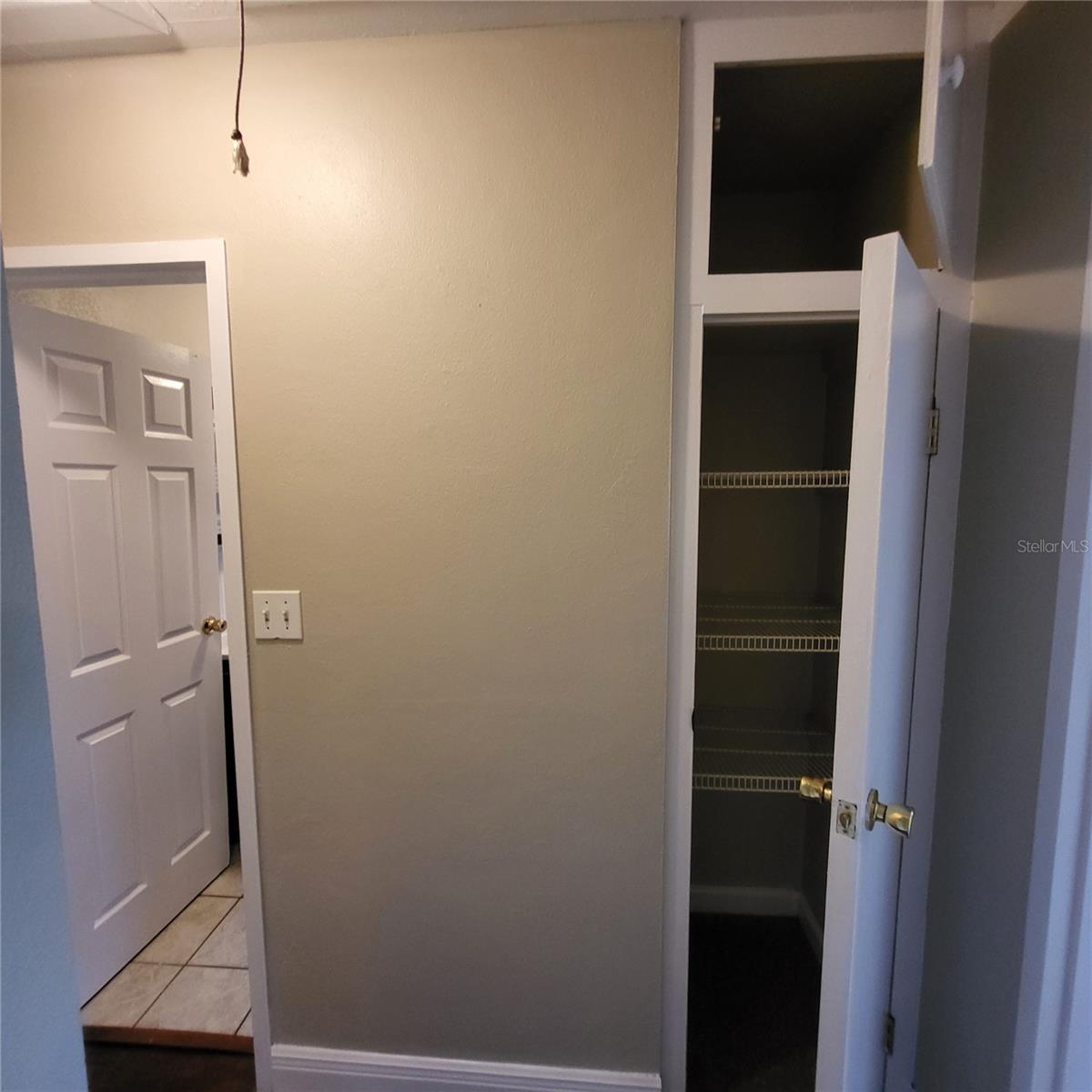 Hall storage closet has shelving and an upper cabinet