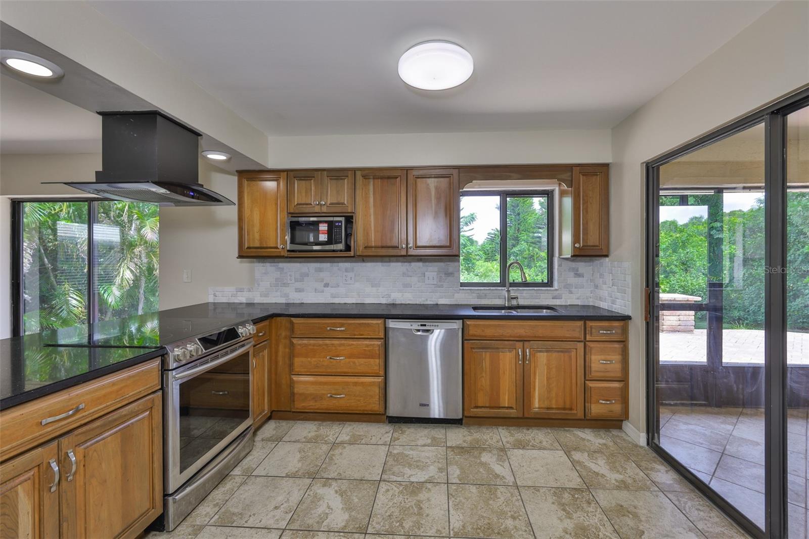 Large kitchen with tons of windows overlooking nature right from the kitchen sink window. This kitchen leads to the lanai and is large enough to entertain plenty of guests. Stainless steel appliances and beautiful onyx colored quartz has silver glitter flaked throughout.
