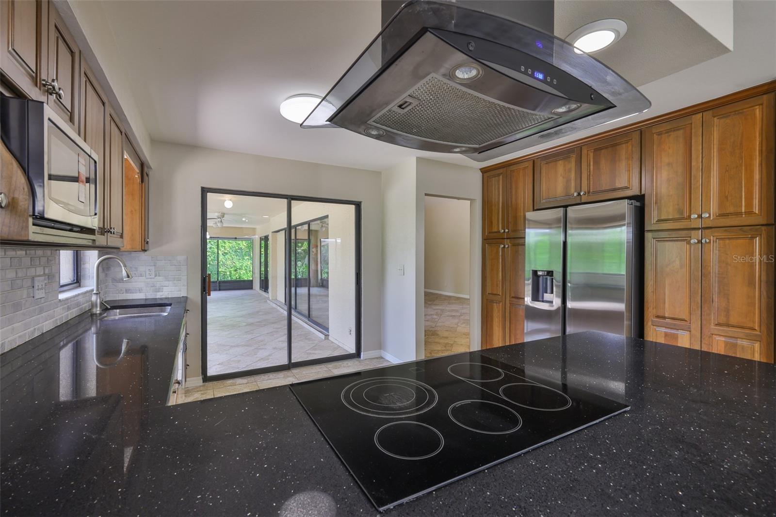 Kitchen boasts of newer stainless steel appliances, modern exhaust hood and cooktop.