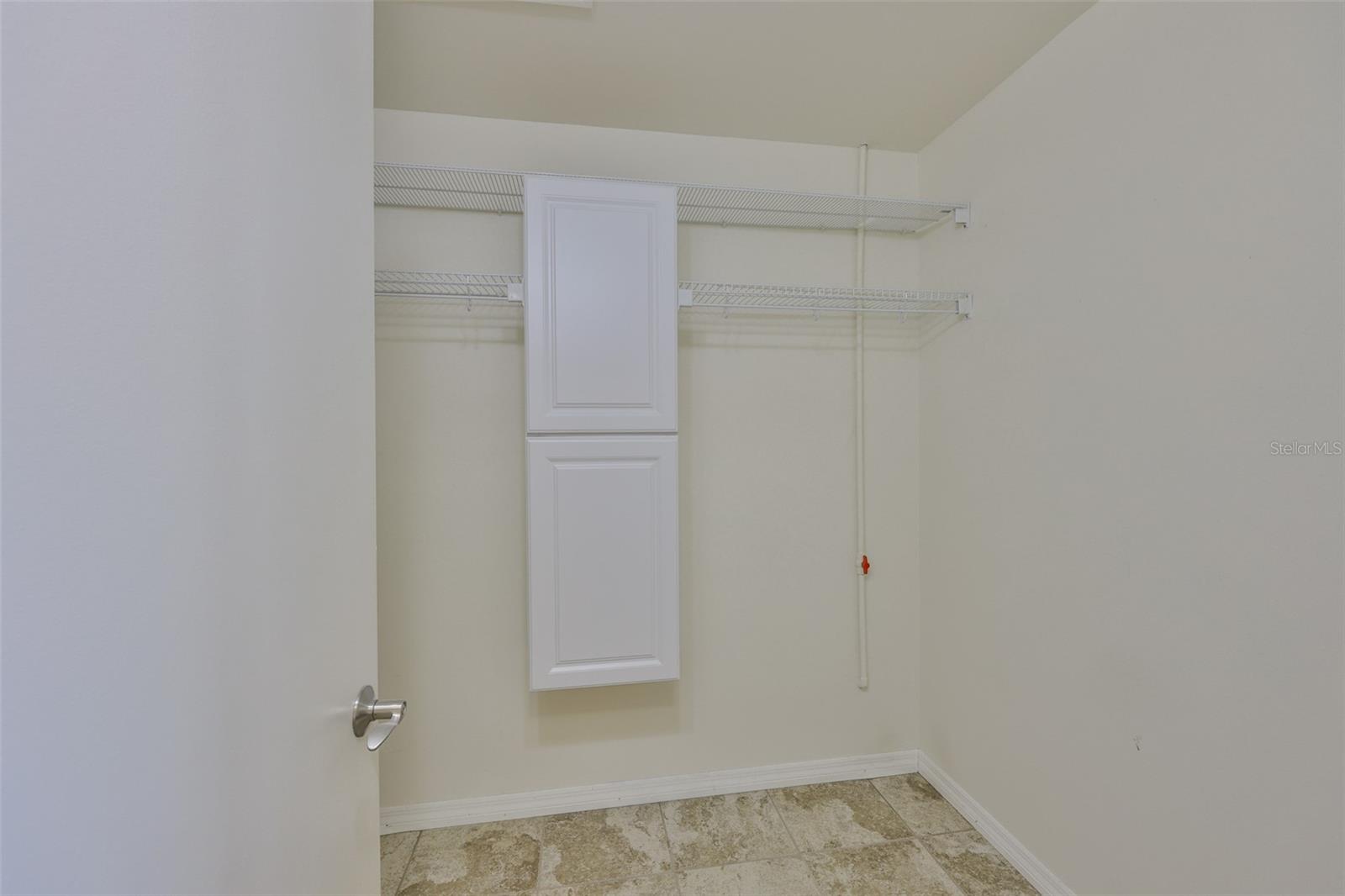 Large tiled walk in primary bedroom closet with shelving offers plenty of space for storing items and clothing.