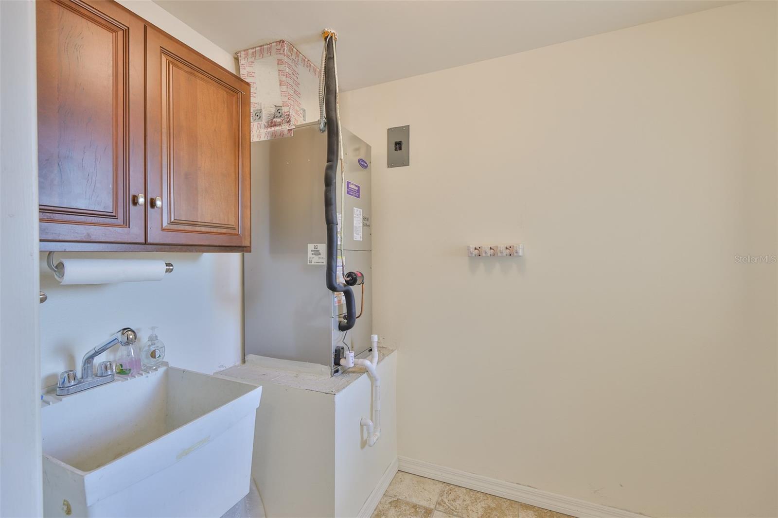 Indoor laundry room offers storage and a deep sink with HVAC handling access.