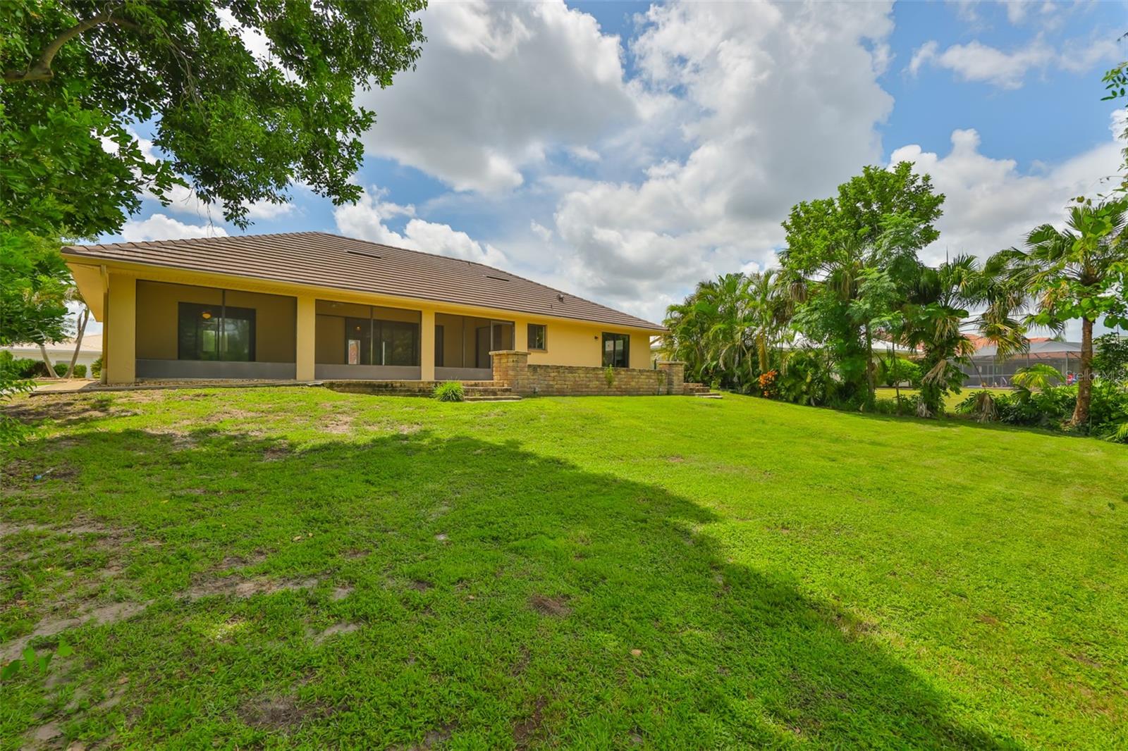 A view of the backyard of the screened in lanai and paved brick patio.