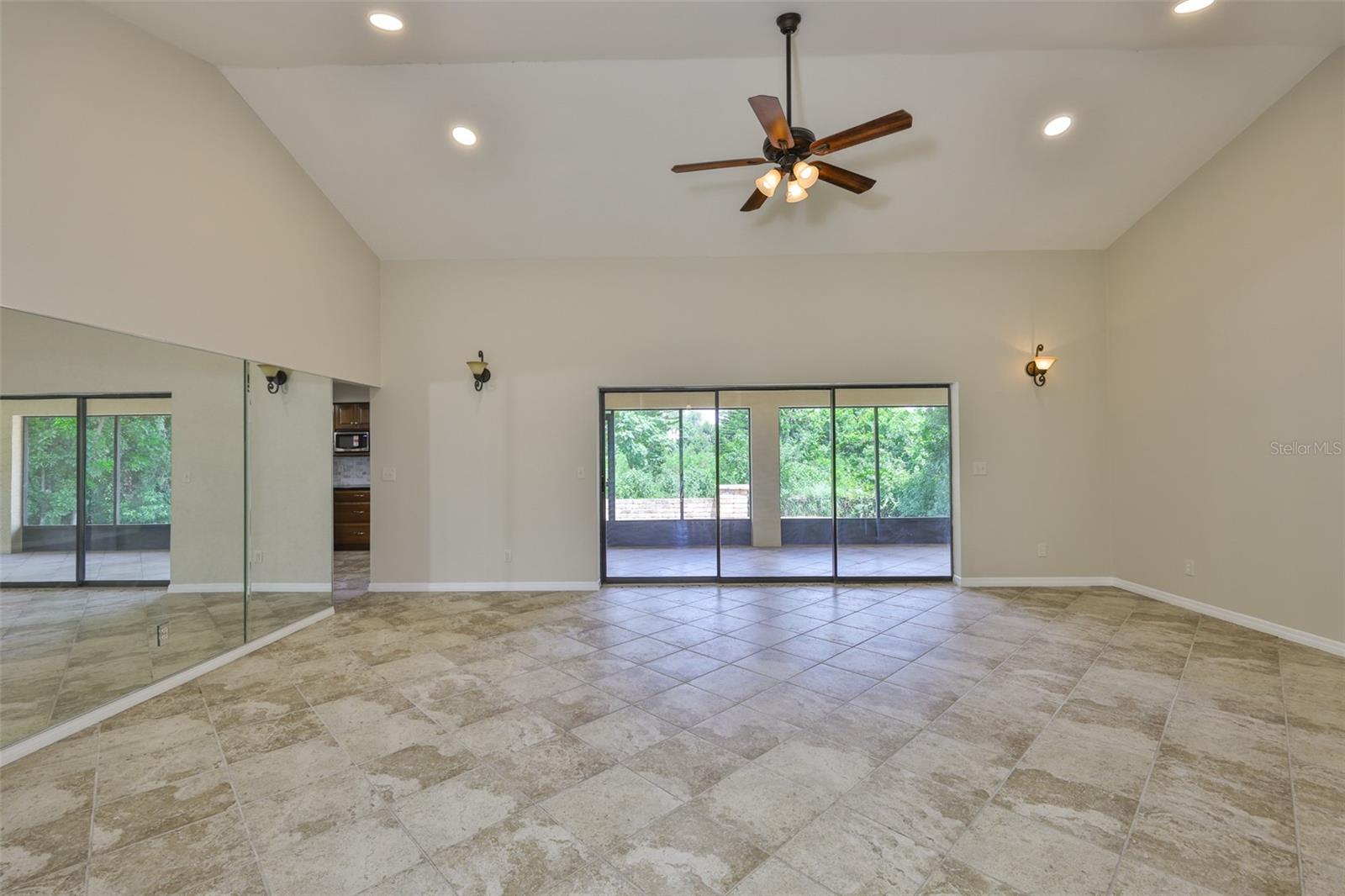 As you walk into the home, large triple sliding glass doors bring the outside in, offering lush views of the woods and landscaping. Notice the continuous flooring throughout the entire home.