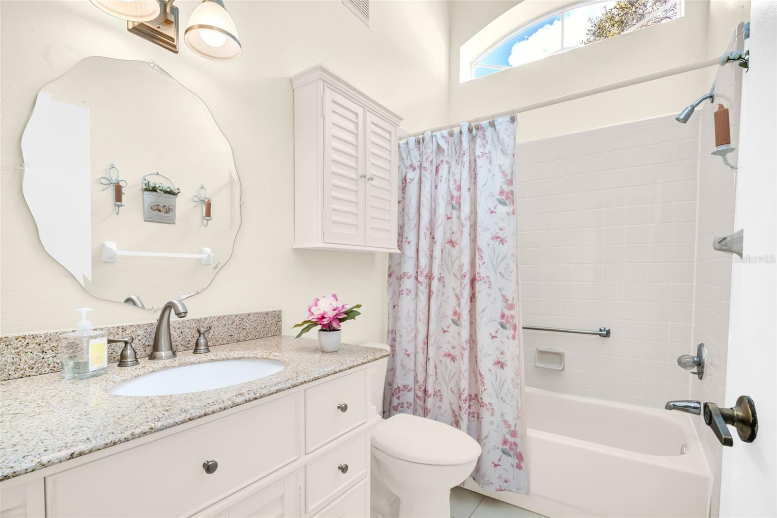 Hall bath with tub/shower combo, vaulted ceilings, and natural lighting~