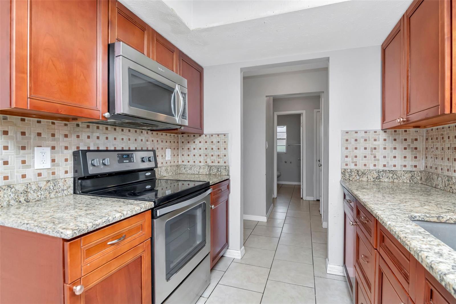 The kitchen features granite counters, tile backsplash, and wood cabinets. The kitchen opens to the foyer and to the dining room.