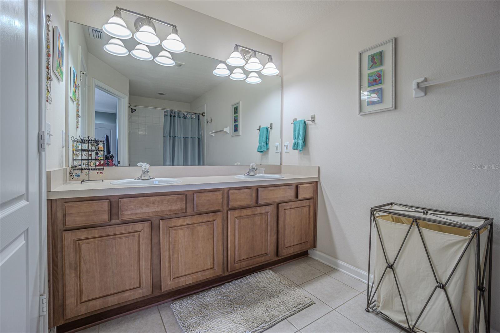 en suite bath with dual sinks, a private water closet and shower/tub combination